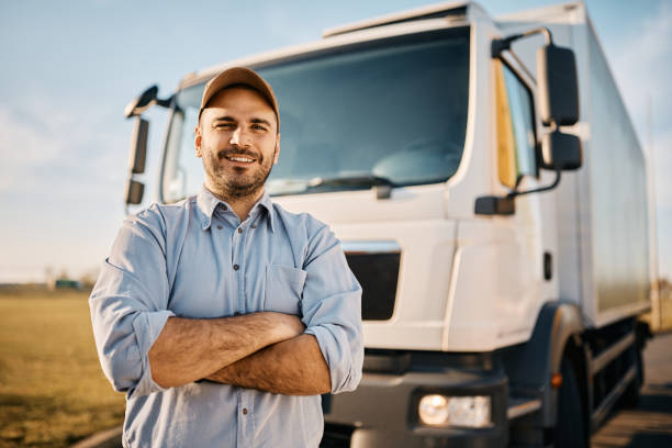 Delivery truck driver standing in front of a large truck.